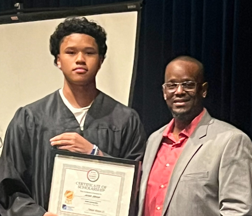 Jordan Johnson, 2024 Century High School graduate and BABC Scholarship recipient, proudly holding his award certificate on stage.